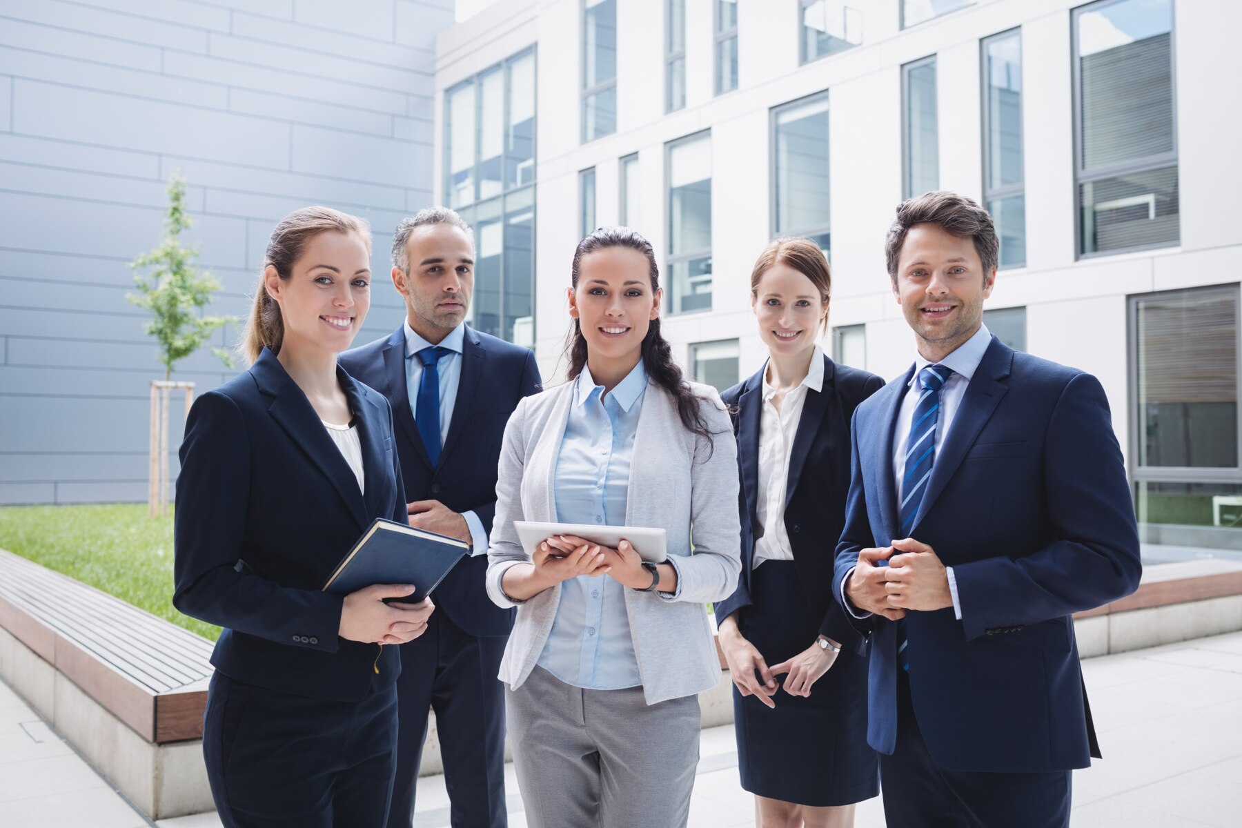 A group of professionals discuss a project in a bright office, reviewing documents and a model while analyzing data on a screen.