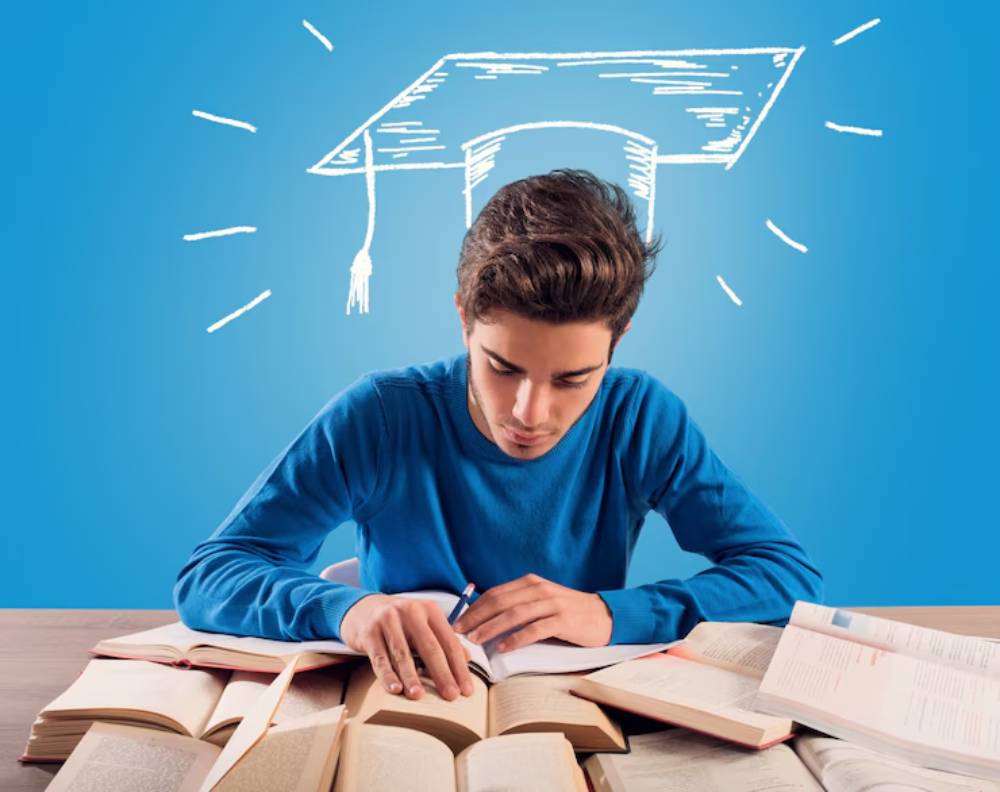 A student in a blue sweater studies diligently at a desk, surrounded by open books, with a graduation cap illustration above.